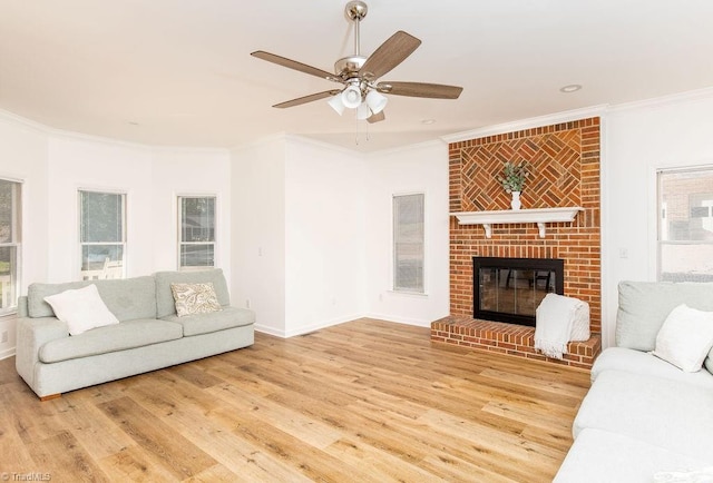 living room with crown molding, hardwood / wood-style flooring, a brick fireplace, and ceiling fan