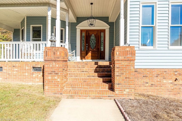 view of exterior entry featuring covered porch