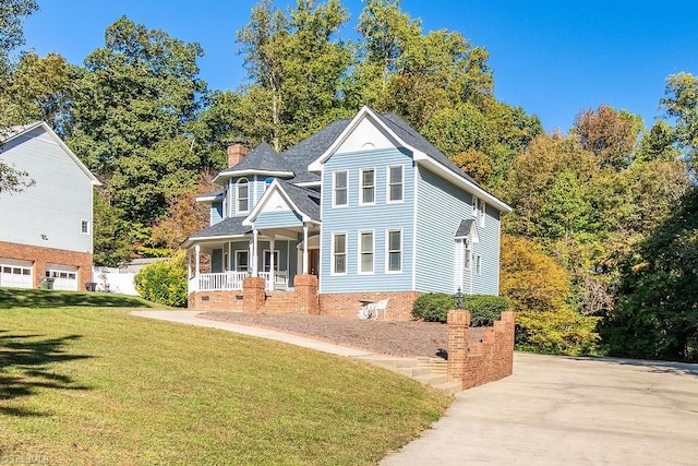 view of front of house with covered porch, a garage, and a front lawn