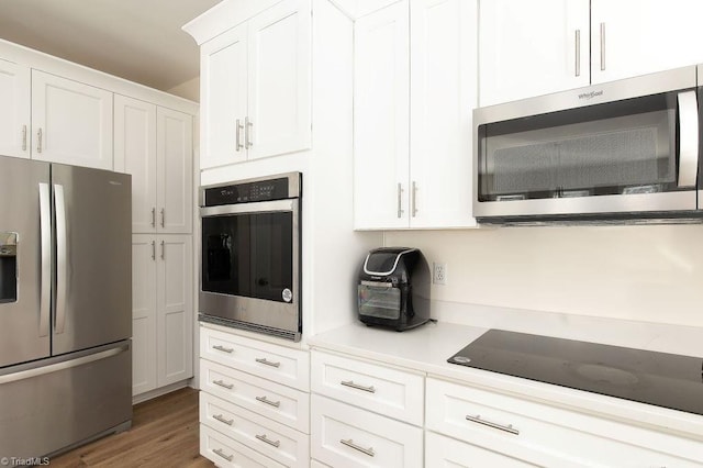 kitchen with dark wood-type flooring, appliances with stainless steel finishes, and white cabinets