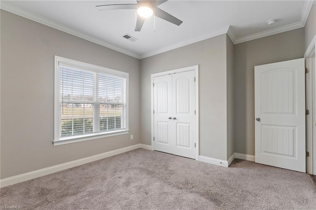 unfurnished bedroom featuring ceiling fan, a closet, light carpet, and crown molding