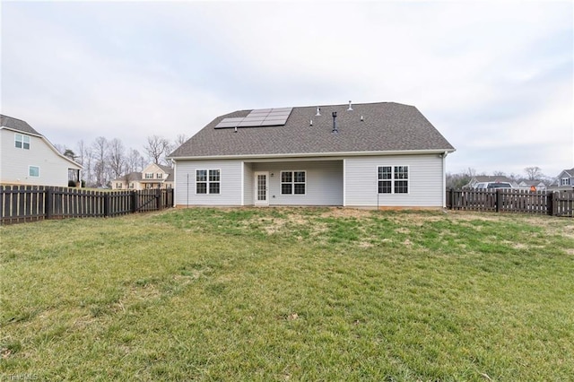 back of house with a lawn and solar panels