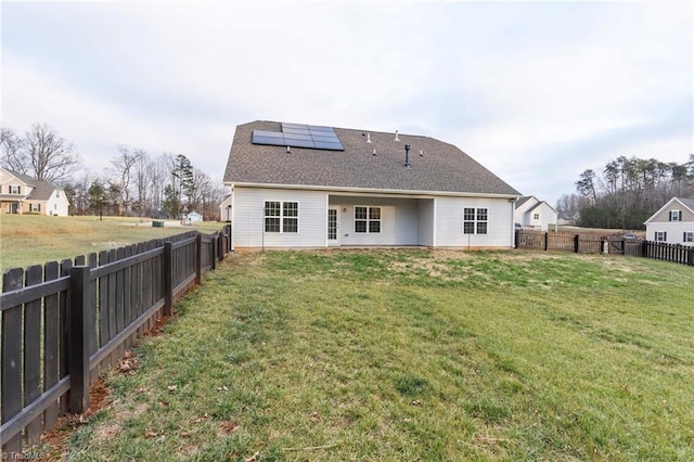 rear view of property with a lawn and solar panels