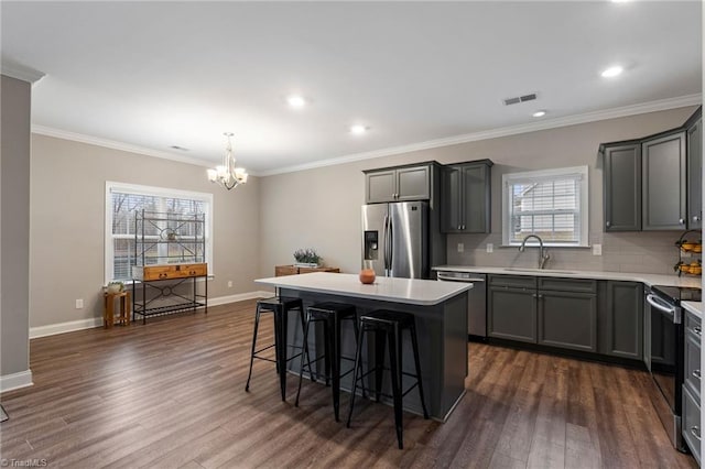 kitchen featuring backsplash, a kitchen island, a breakfast bar, sink, and appliances with stainless steel finishes