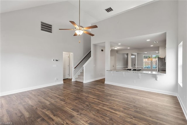 unfurnished living room featuring dark wood-type flooring, ceiling fan, and high vaulted ceiling