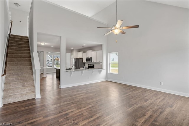 unfurnished living room featuring high vaulted ceiling, dark hardwood / wood-style floors, and ceiling fan