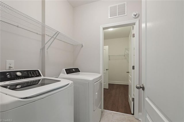 clothes washing area featuring washing machine and clothes dryer and light tile patterned floors