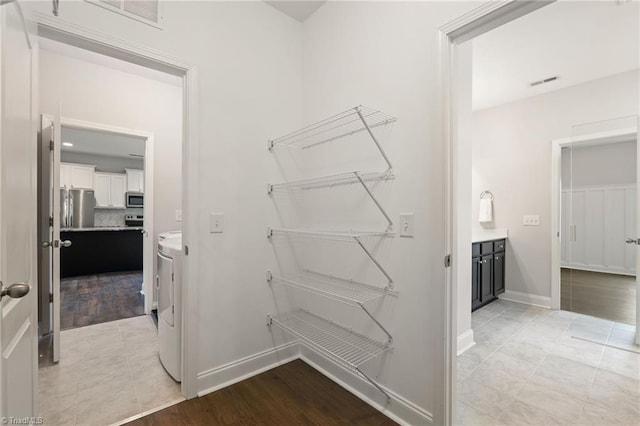 walk in closet with light hardwood / wood-style flooring and washer and clothes dryer