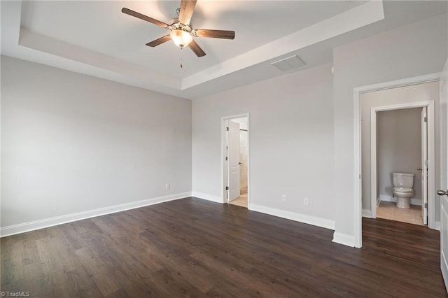 unfurnished room with a raised ceiling, dark hardwood / wood-style floors, and ceiling fan