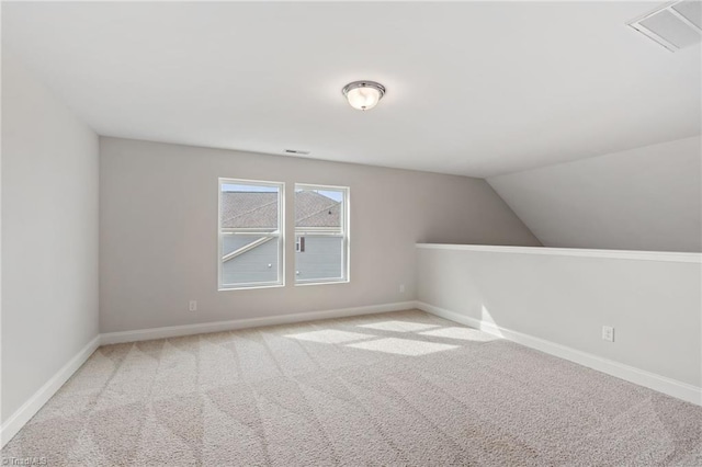 additional living space featuring lofted ceiling and light carpet