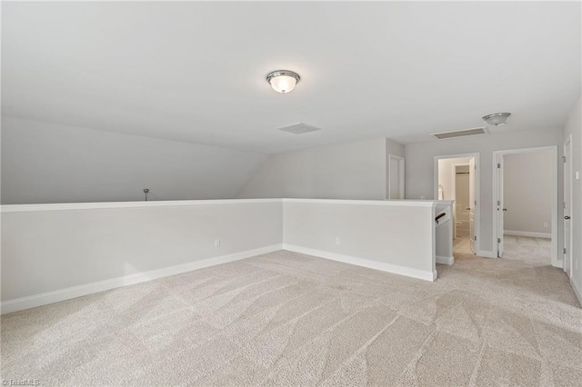 additional living space featuring lofted ceiling and light carpet