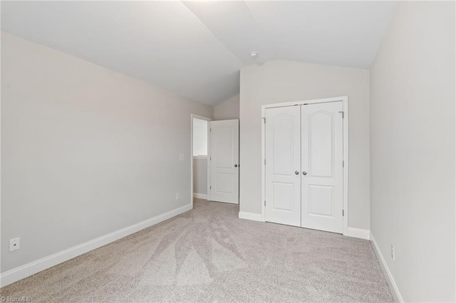 unfurnished bedroom featuring lofted ceiling, light carpet, and a closet