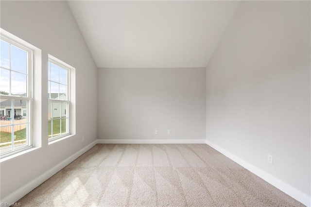 carpeted empty room featuring lofted ceiling