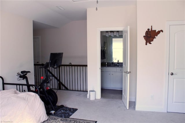 bedroom with light colored carpet, vaulted ceiling, baseboards, and ensuite bathroom