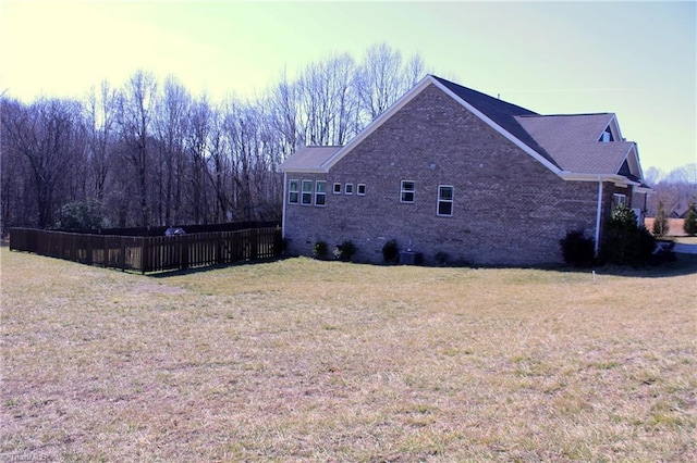 view of home's exterior featuring brick siding, fence, and a yard