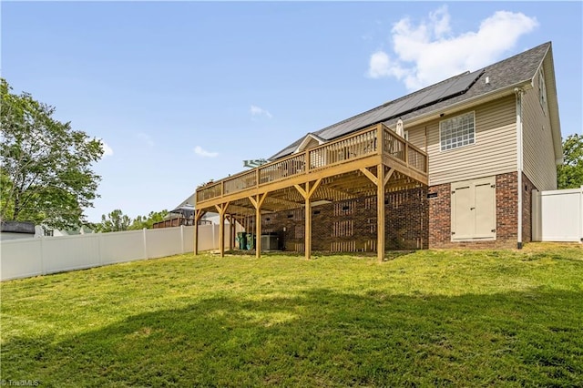 rear view of house with a fenced backyard, a wooden deck, a yard, and brick siding