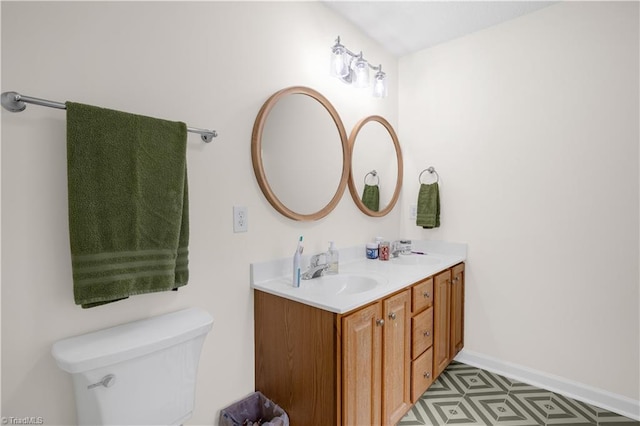 bathroom featuring a sink, baseboards, toilet, and double vanity