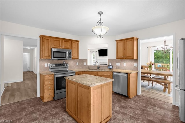 kitchen featuring backsplash, decorative light fixtures, a center island, a sink, and stainless steel appliances