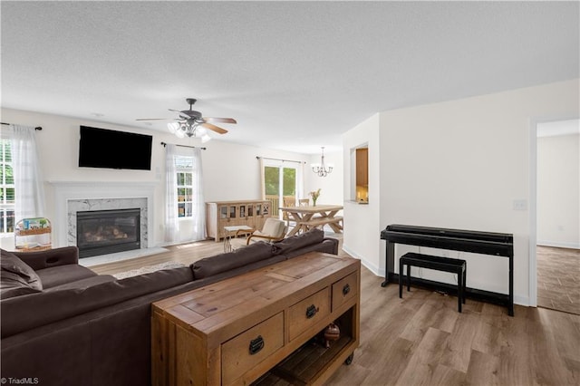 living room with light wood-style flooring, ceiling fan with notable chandelier, and a fireplace