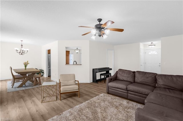 living area with baseboards, ceiling fan with notable chandelier, and wood finished floors