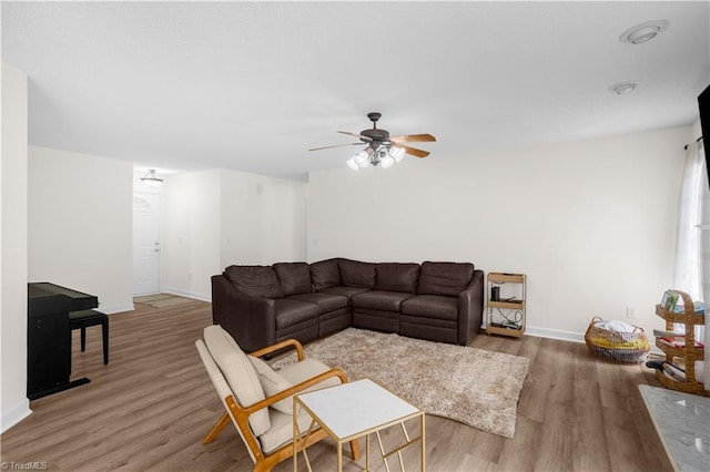 living area featuring baseboards, ceiling fan, and light wood finished floors