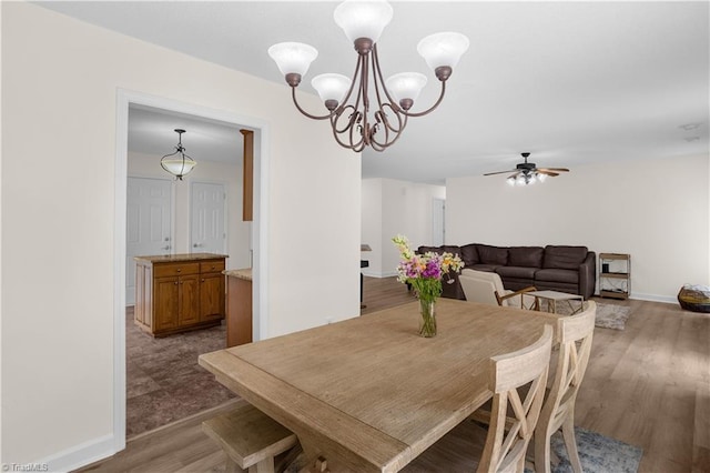 dining space featuring baseboards, ceiling fan with notable chandelier, and wood finished floors