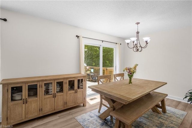 dining area featuring a textured ceiling, light wood-style flooring, and a notable chandelier