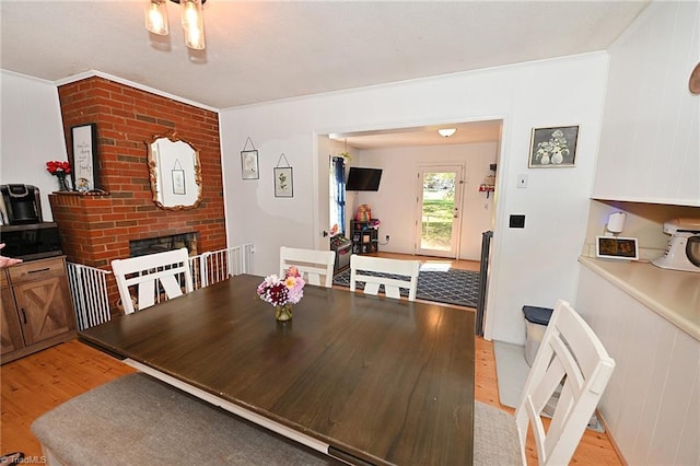 dining area with light hardwood / wood-style flooring, wood walls, a fireplace, and crown molding