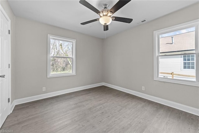 spare room with visible vents, baseboards, ceiling fan, and wood finished floors