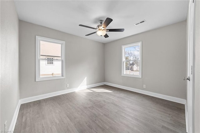 spare room featuring a ceiling fan, wood finished floors, visible vents, and baseboards