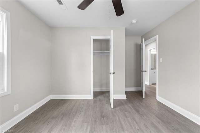 unfurnished bedroom featuring a closet, visible vents, a ceiling fan, wood finished floors, and baseboards