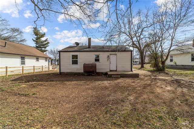 back of house with crawl space, heating fuel, a chimney, and fence