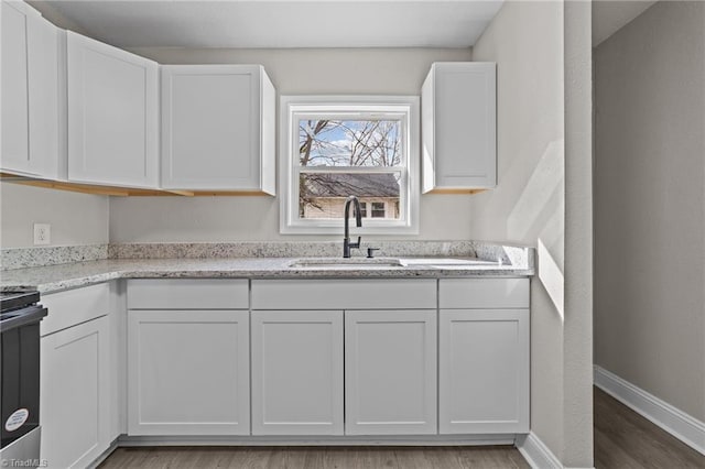 kitchen with white cabinets, a sink, stainless steel electric range, and baseboards