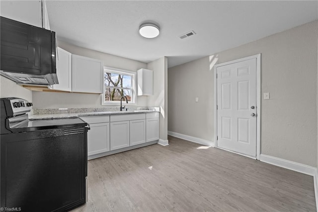 kitchen with electric range, light wood-style floors, visible vents, and white cabinetry