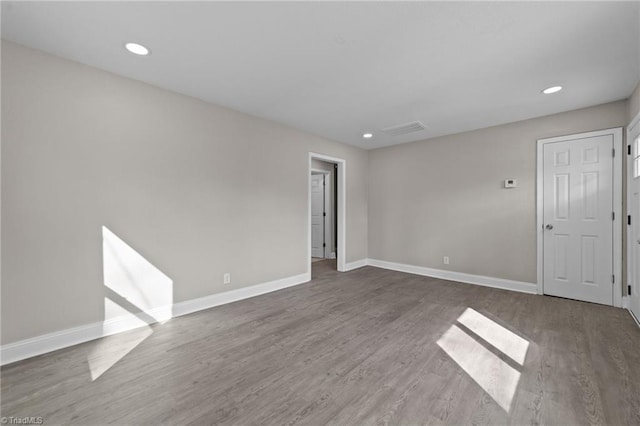 spare room featuring recessed lighting, wood finished floors, and baseboards