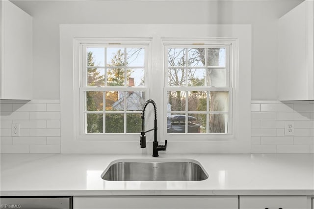 kitchen featuring sink, dishwashing machine, and white cabinets