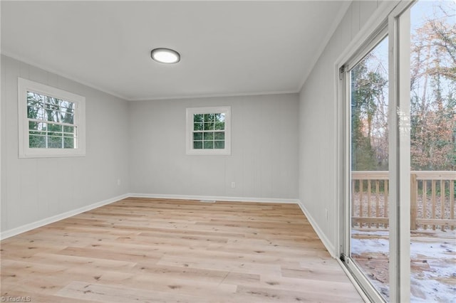 spare room featuring a wealth of natural light, ornamental molding, and light hardwood / wood-style floors