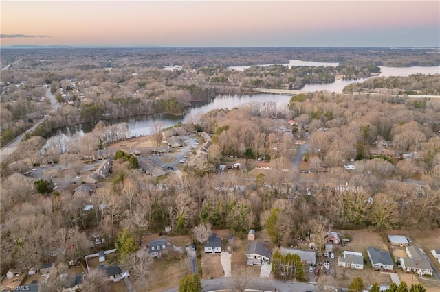 aerial view at dusk featuring a water view