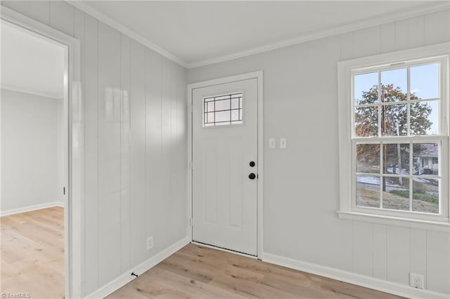 foyer entrance featuring wood walls, crown molding, and light hardwood / wood-style floors