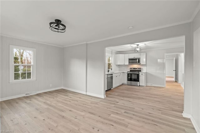 kitchen featuring stainless steel appliances, crown molding, light hardwood / wood-style flooring, and white cabinetry