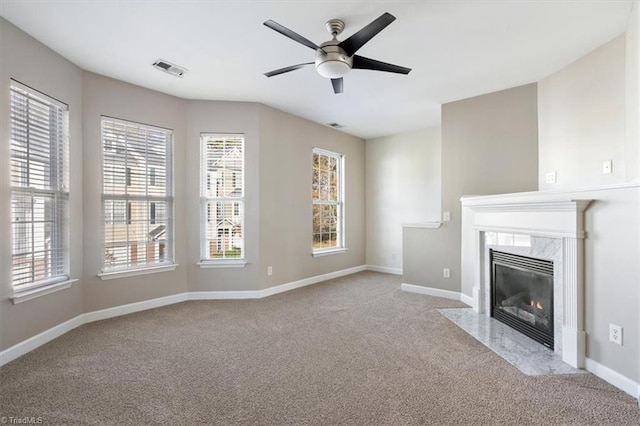 unfurnished living room with a high end fireplace, light colored carpet, and ceiling fan