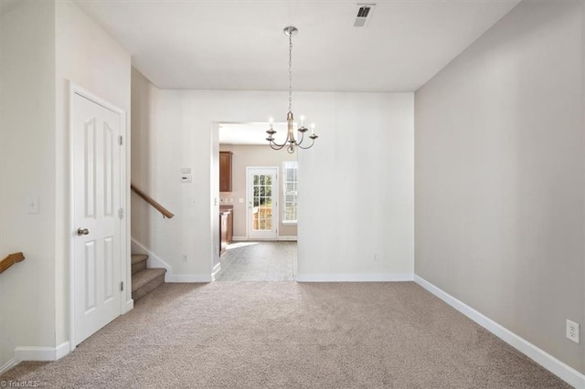 empty room featuring light colored carpet and an inviting chandelier