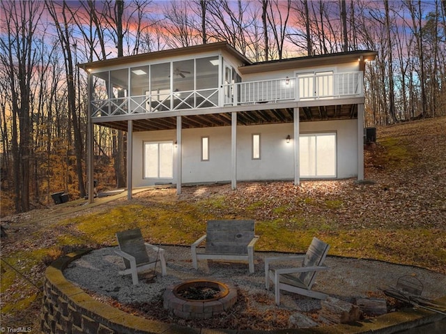 back house at dusk featuring a fire pit and a sunroom