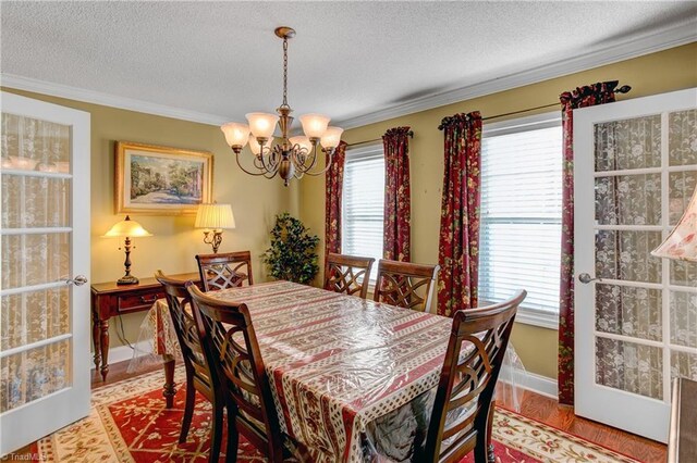 dining room featuring a textured ceiling, light hardwood / wood-style floors, ornamental molding, and a notable chandelier