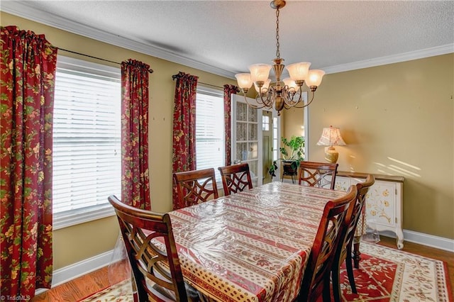 dining room with a textured ceiling, hardwood / wood-style flooring, crown molding, and a notable chandelier