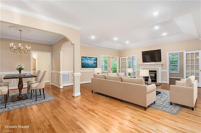 2012 Muirfield Ct, Elon, NC 27244 - living area featuring light wood finished floors, healthy amount of natural light, a glass covered fireplace, a chandelier, and crown molding