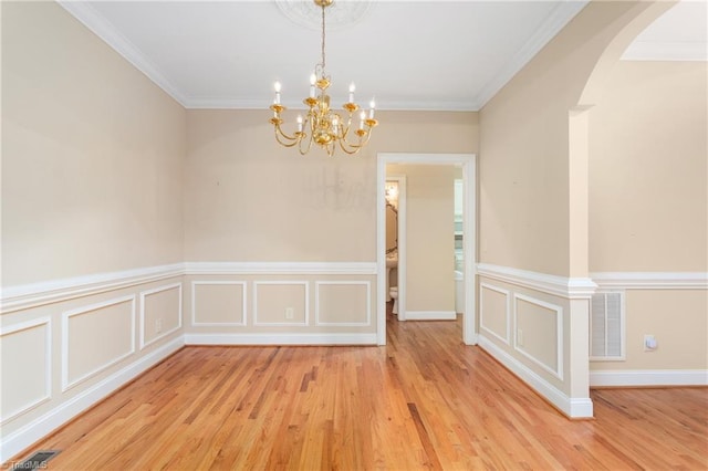 2012 Muirfield Ct, Elon, NC 27244 - unfurnished room with a chandelier, light wood-style flooring, crown molding, arched walkways, and a wainscoted wall