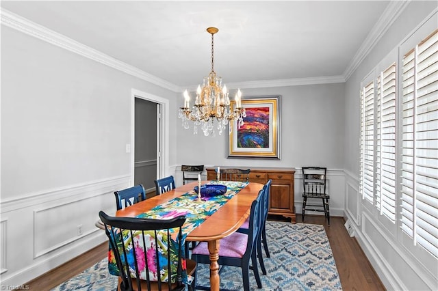 dining space featuring a chandelier, dark wood-type flooring, crown molding, a decorative wall, and a wainscoted wall