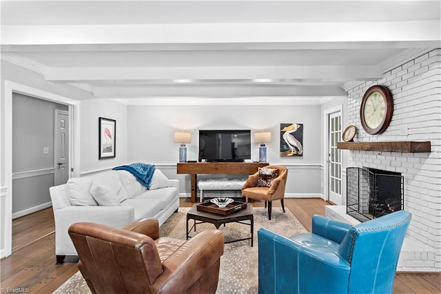 living room featuring beam ceiling, a fireplace, wood finished floors, and crown molding