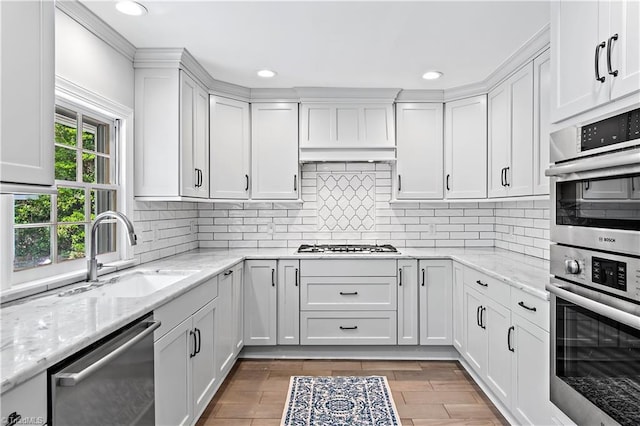 kitchen with appliances with stainless steel finishes, a sink, recessed lighting, white cabinets, and tasteful backsplash